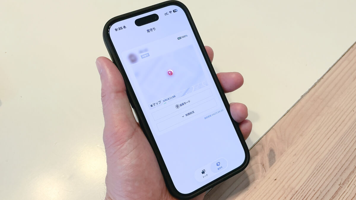 TONEモバイルの見守り画面を表示したスマホを手に持つ様子